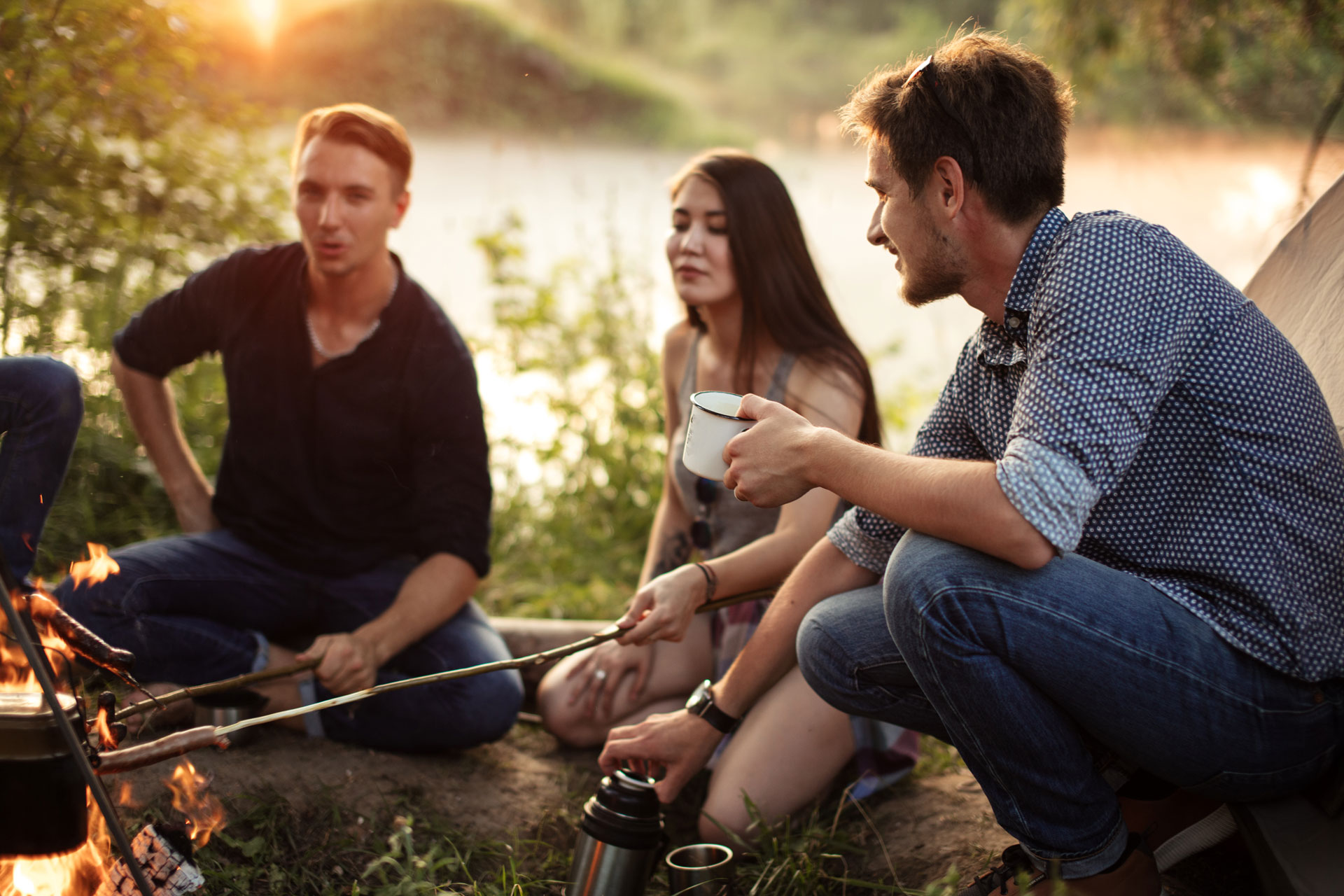 Friends enjoying a peaceful camping evening by a lake, a setting conducive to wellness and recovery.