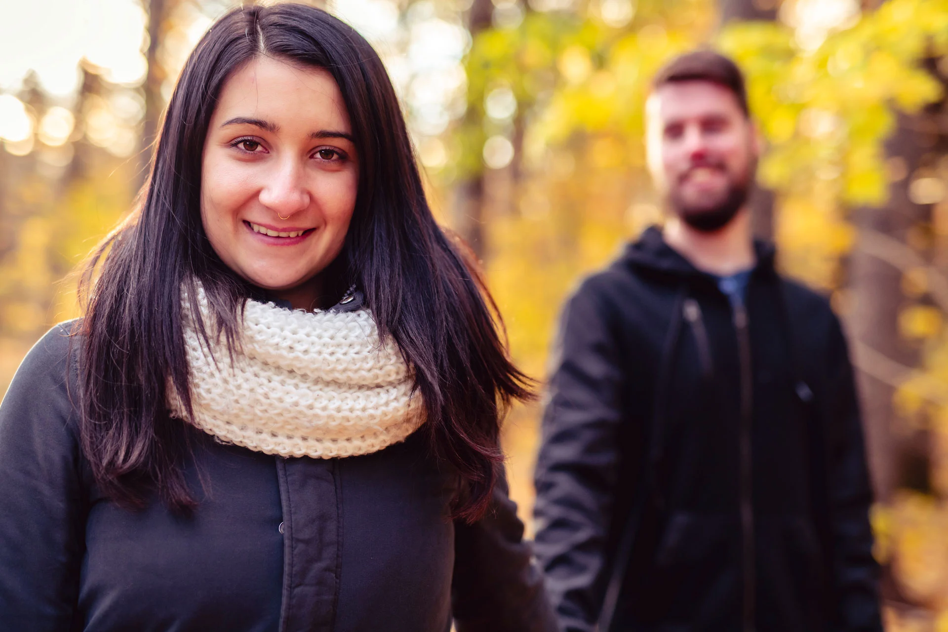 happy woman in focus with man in background, autumn setting conveying a peaceful walk for anxiety management