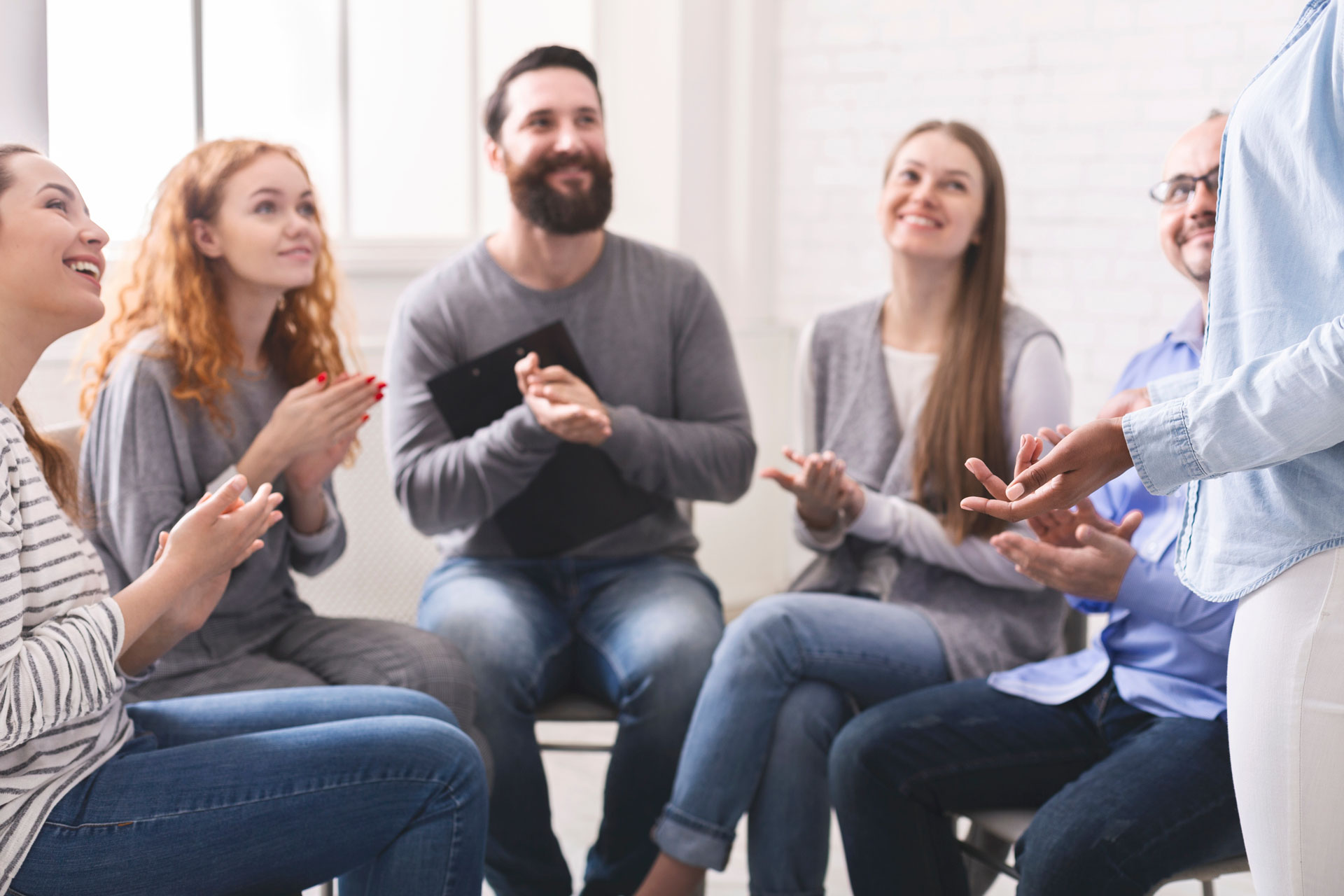 Group therapy participants engaged in a supportive conversation, indicative of a recovery program Group therapy participants engaged in a supportive conversation, indicative of a recovery program