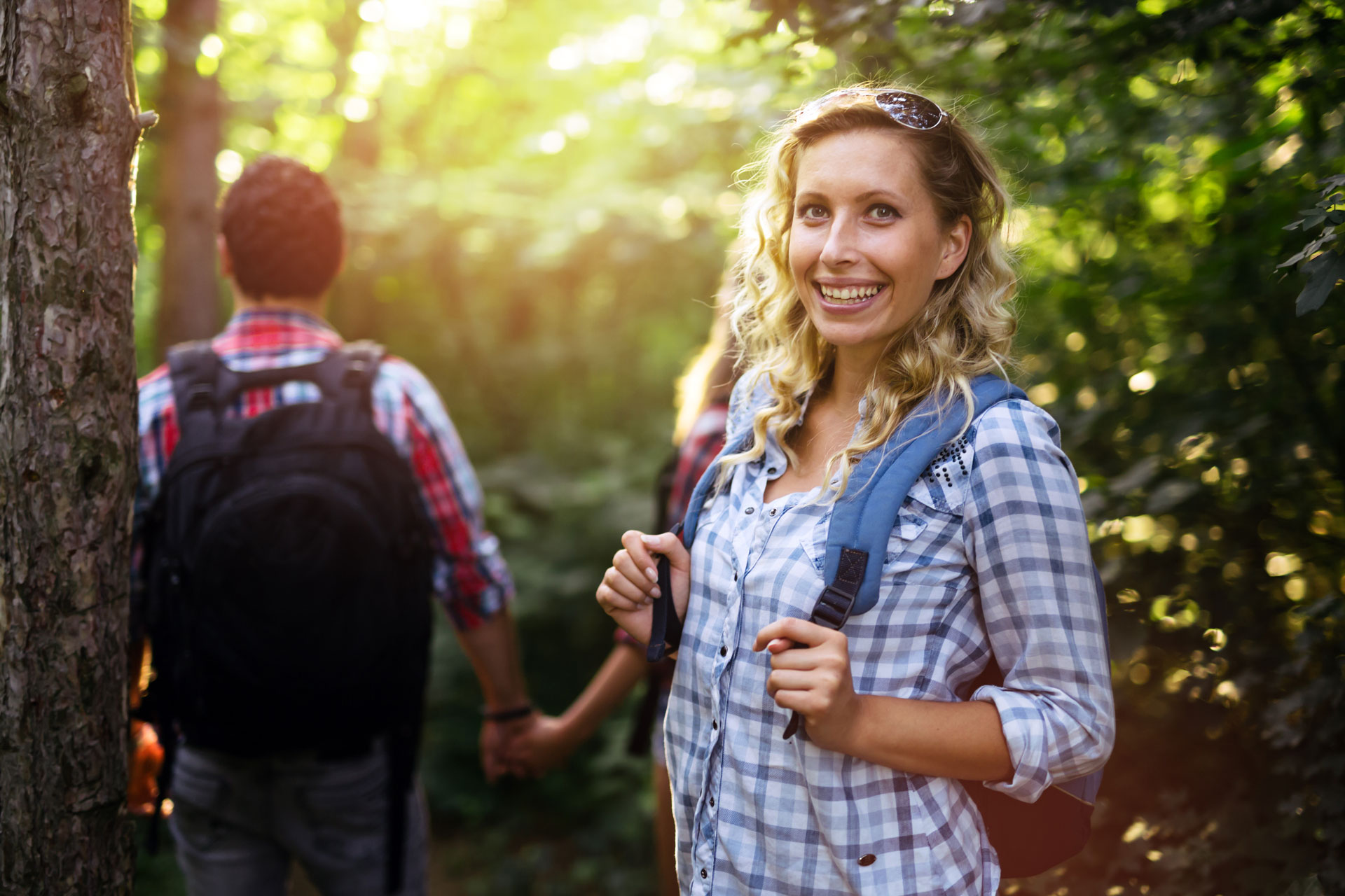 Woman hiking with a friend in the woods, smiling, enjoying nature’s therapeutic ambiance.