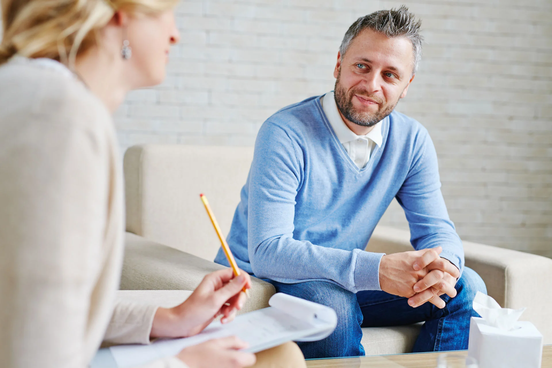 therapist with clipboard providing psychological recovery support to a man
