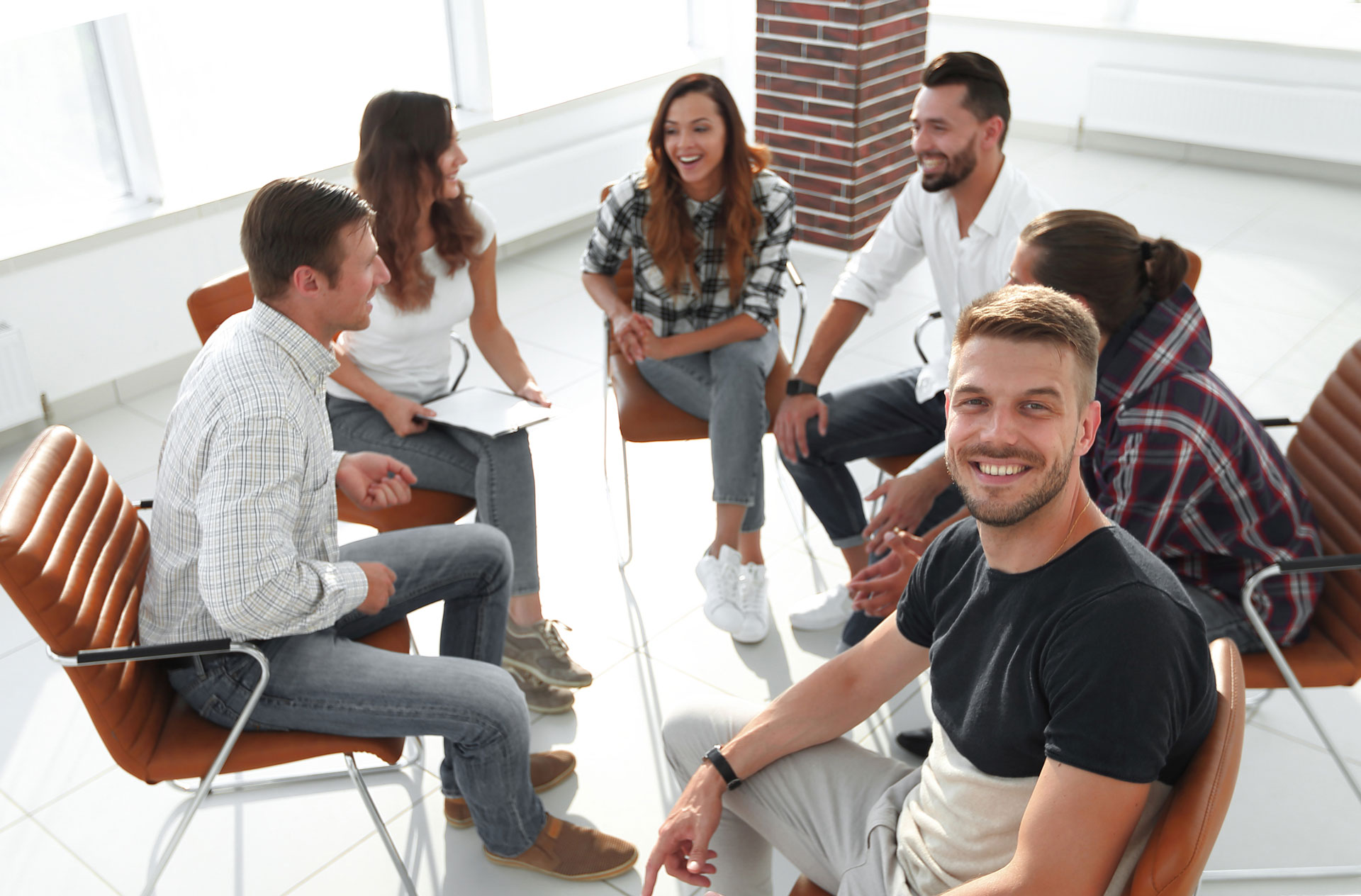 Group of people smiling and sharing experiences in an Addiction Recovery Support meeting Group of people smiling and sharing experiences in an Addiction Recovery Support meeting