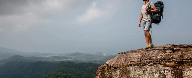 a hiker stands on a high cliff overlooking a vast mountain range, symbolizing peace and gratitude in recovery.