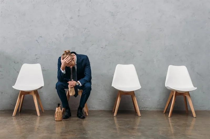 a lonely businessman holding a bottle, showing how alcohol affects physical and mental health, leading to alcohol-related disease.