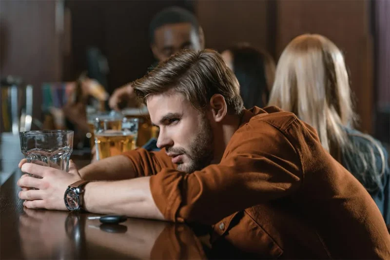 a man binge-drinking alcohol inside a pub.