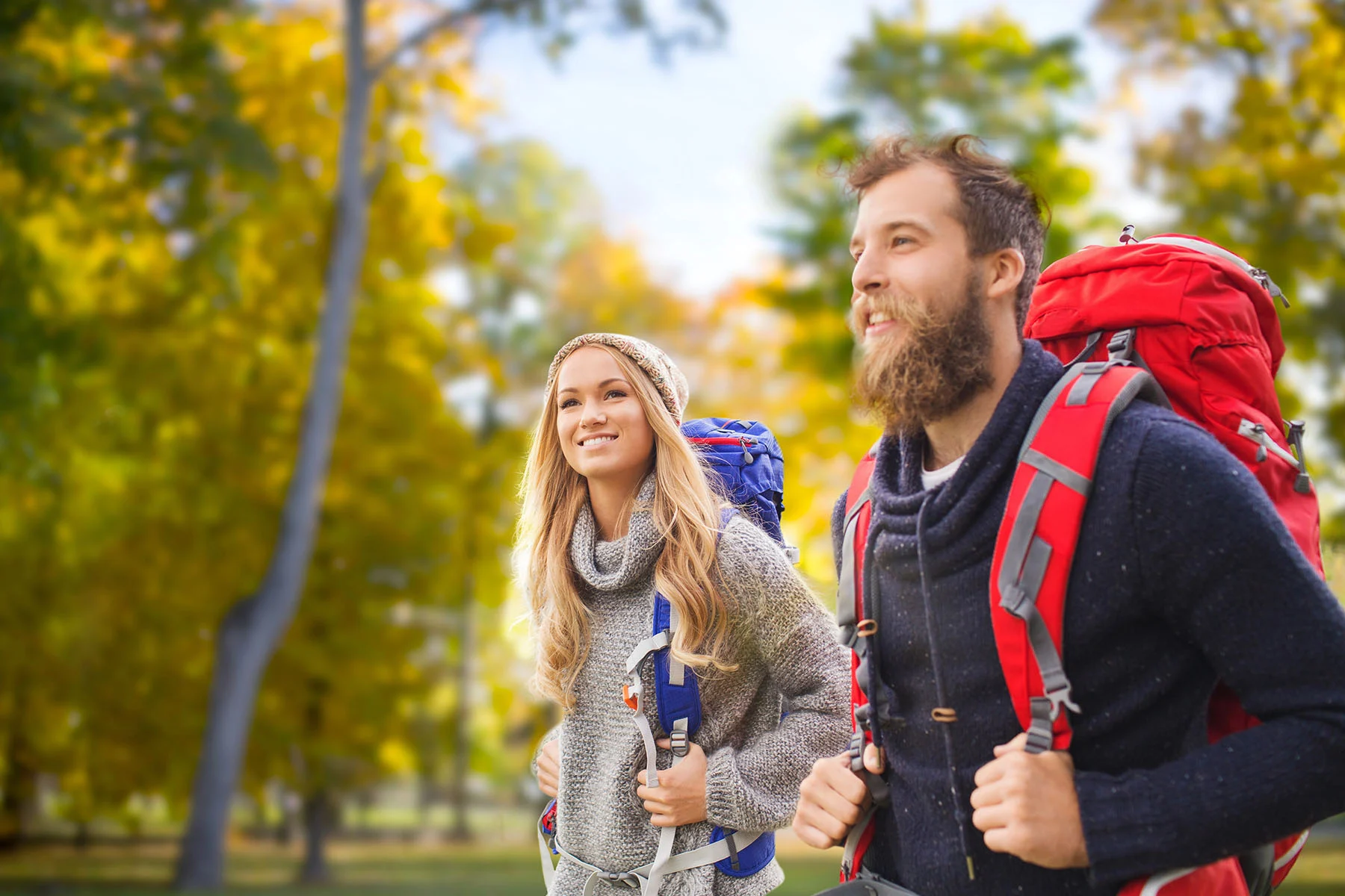 a smiling couple enjoys a hike in a sunny, wooded area, symbolizing the positive outcomes of effective treatment for kratom addiction.