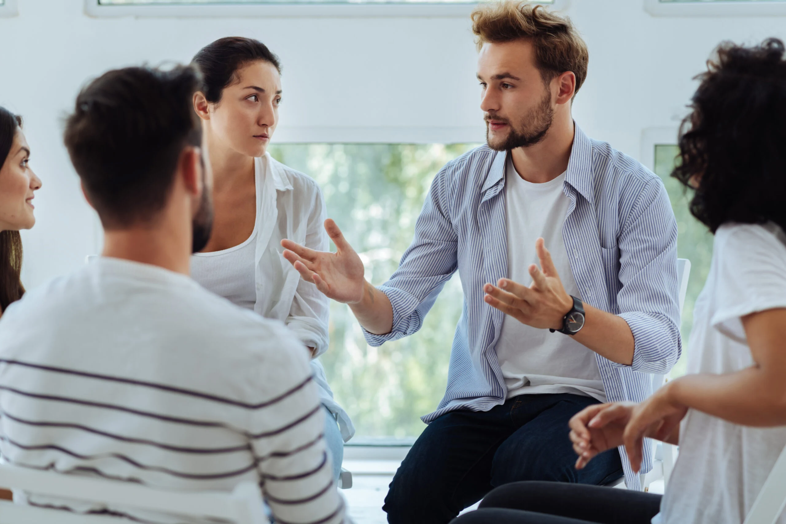 man gesturing while talking in a group therapy session, evoking mental health support