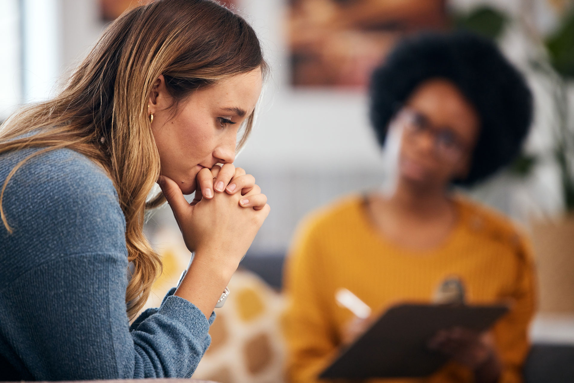 Woman in trauma counseling session with a therapist taking notes Woman in trauma counseling session with a therapist taking notes