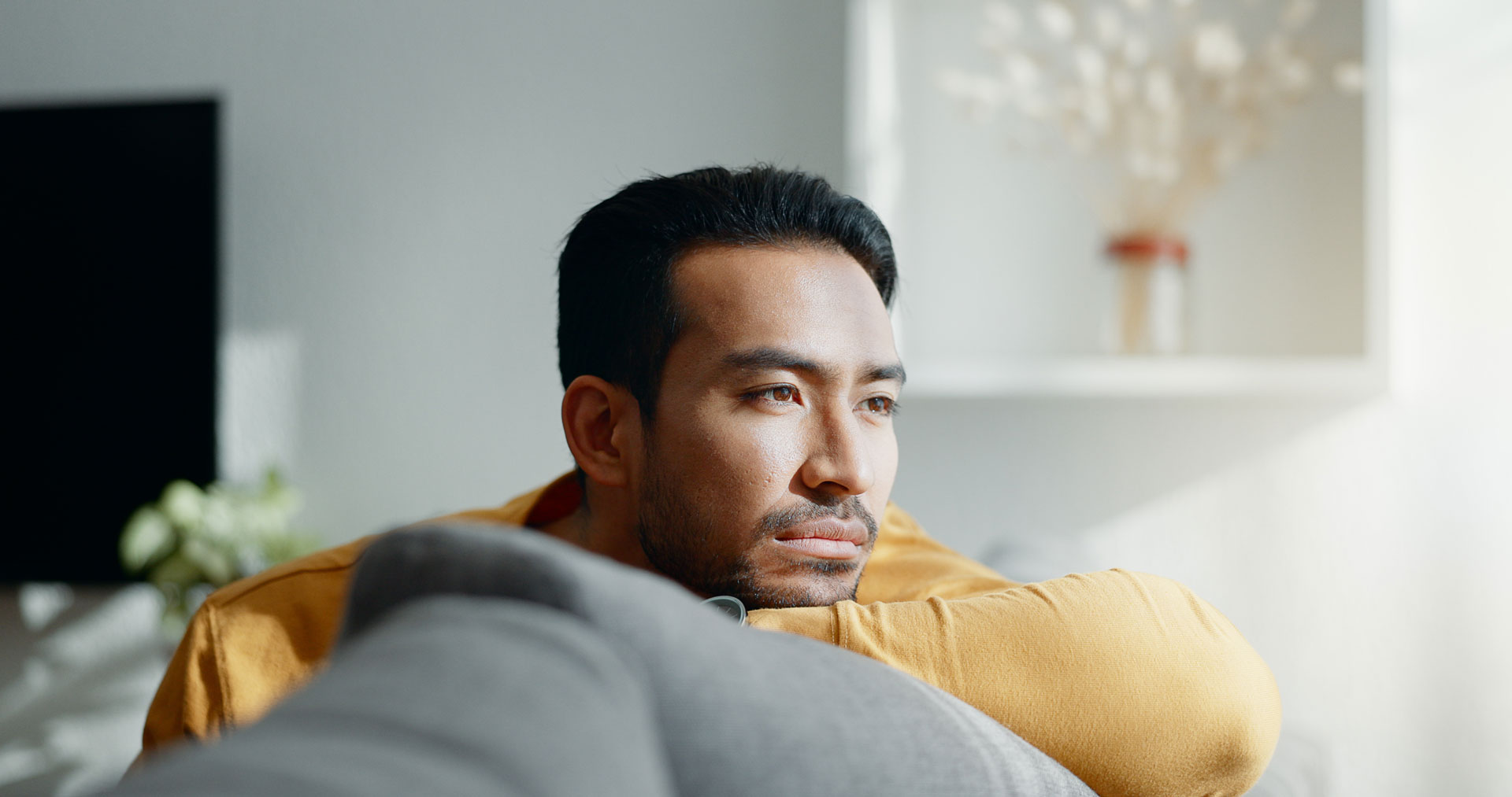Man reflecting on his PTSD therapy session, sitting calmly on a couch, gazing out the window Man reflecting on his cognitive processing therapy session, sitting calmly on a couch, gazing out the window