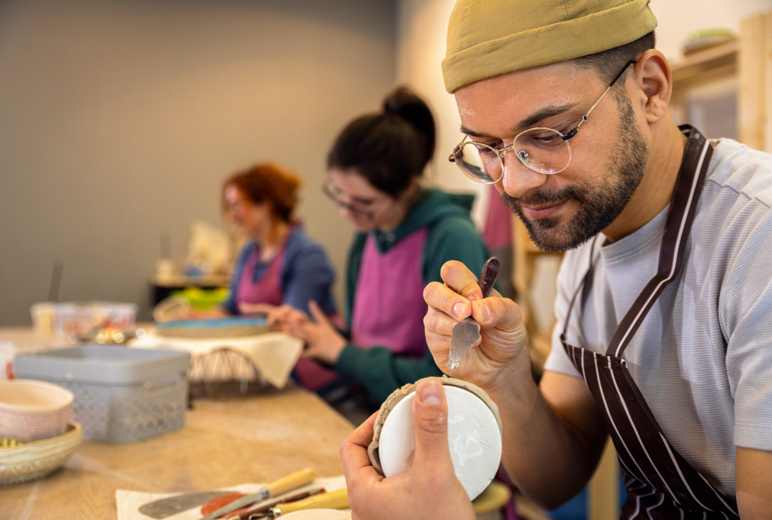 focused man enjoying a pottery class, highlighting creative therapy activities.