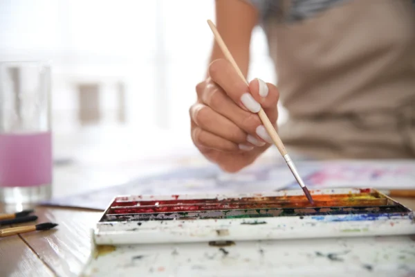 Close-Up Of A Hand Using A Paintbrush With Watercolors, Symbolizing Art Therapy And Pacificsource Substance Abuse Coverage. close-up of a hand using a paintbrush with watercolors, symbolizing art therapy and pacificsource substance abuse coverage.