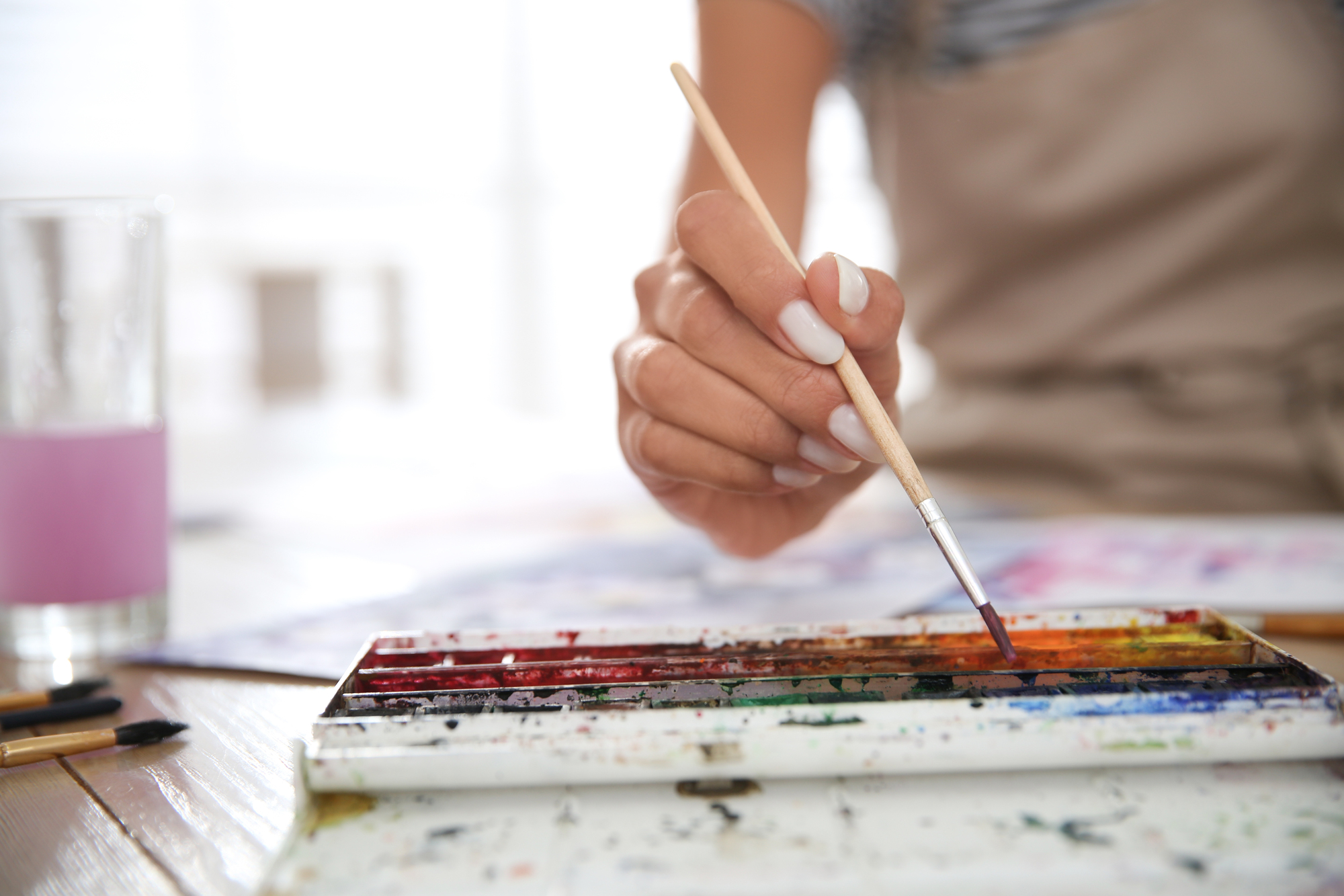 Close-up of a hand using a paintbrush with watercolors, symbolizing art therapy and PacificSource substance abuse coverage.