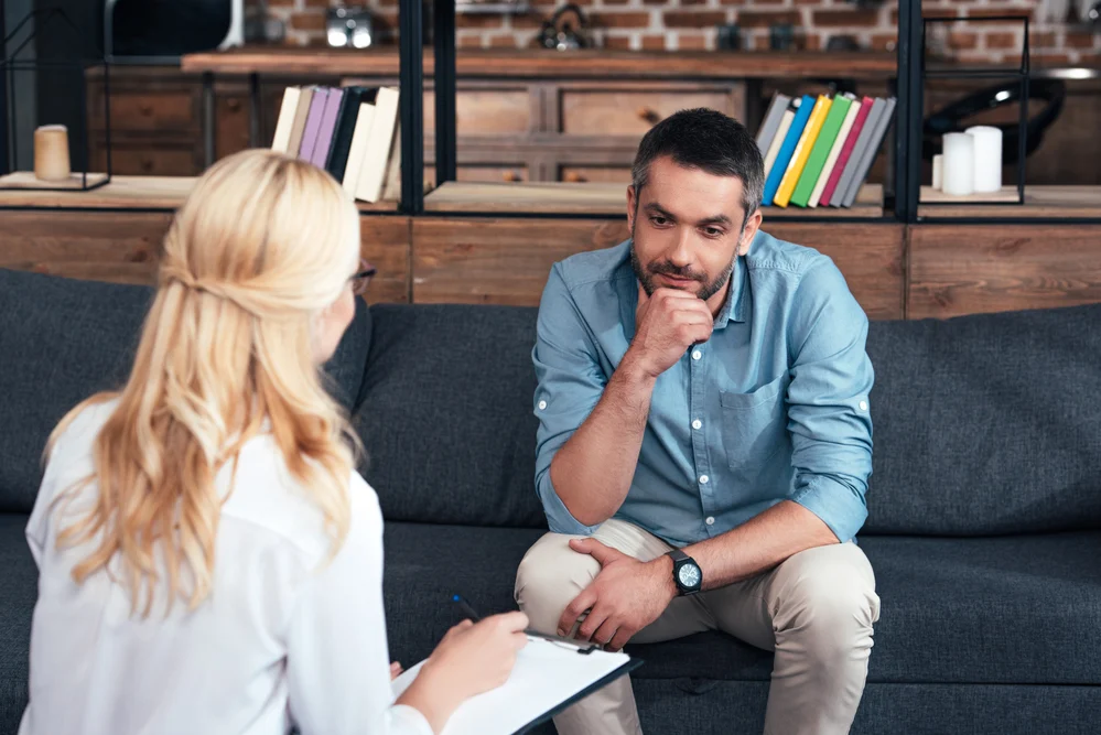 Thoughtful Man In Counseling With Attentive Therapist, Discussing Strategies For Stress Relief thoughtful man in counseling with attentive therapist, discussing his past traumas