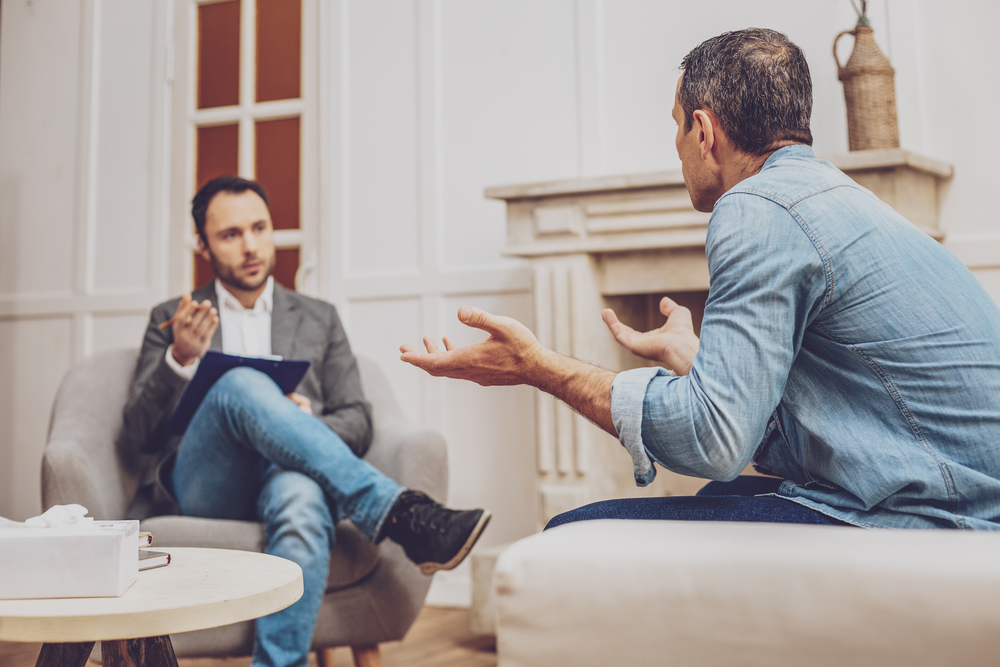 man in a therapy session discussing his feelings with a psychologist, signifying mental health counseling.