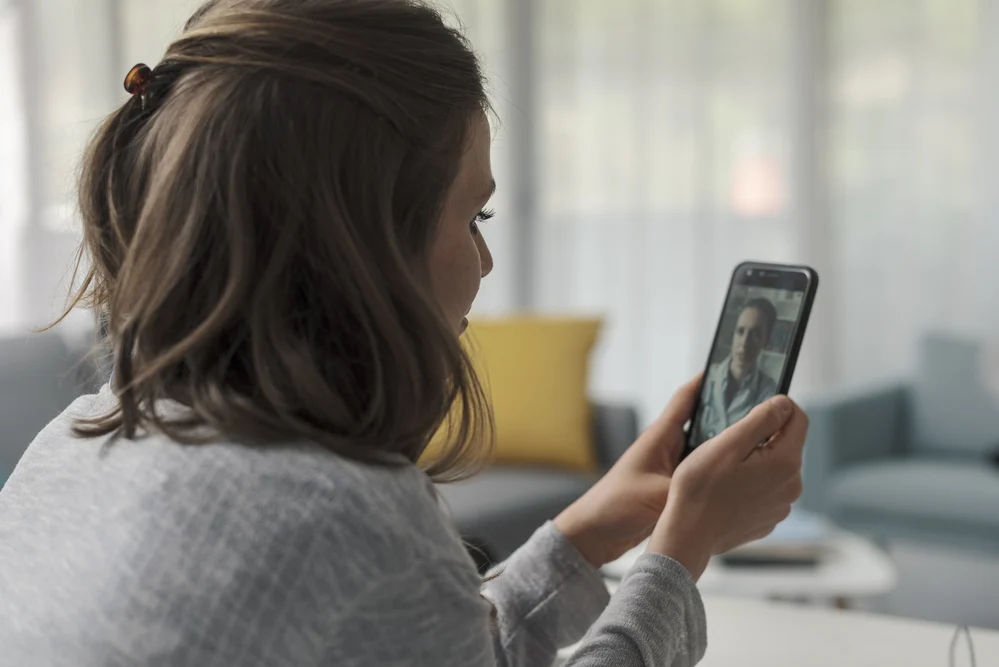 woman in a telehealth session with a healthcare professional on her smartphone.