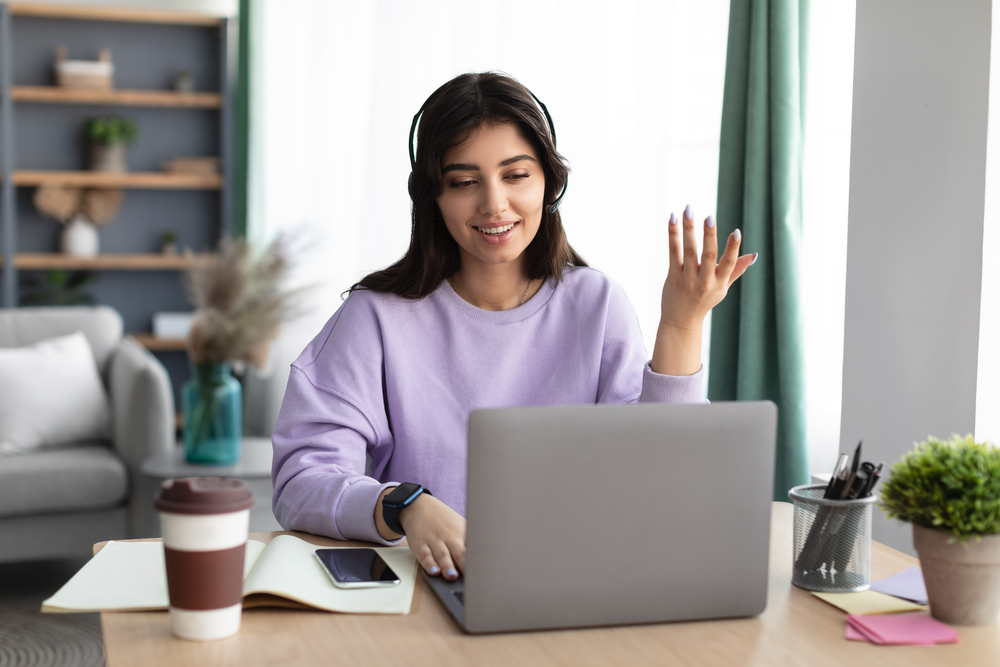 Woman in headphones having videocall using laptop, talking and gesturing Individual in an online counseling session with a therapist using a laptop