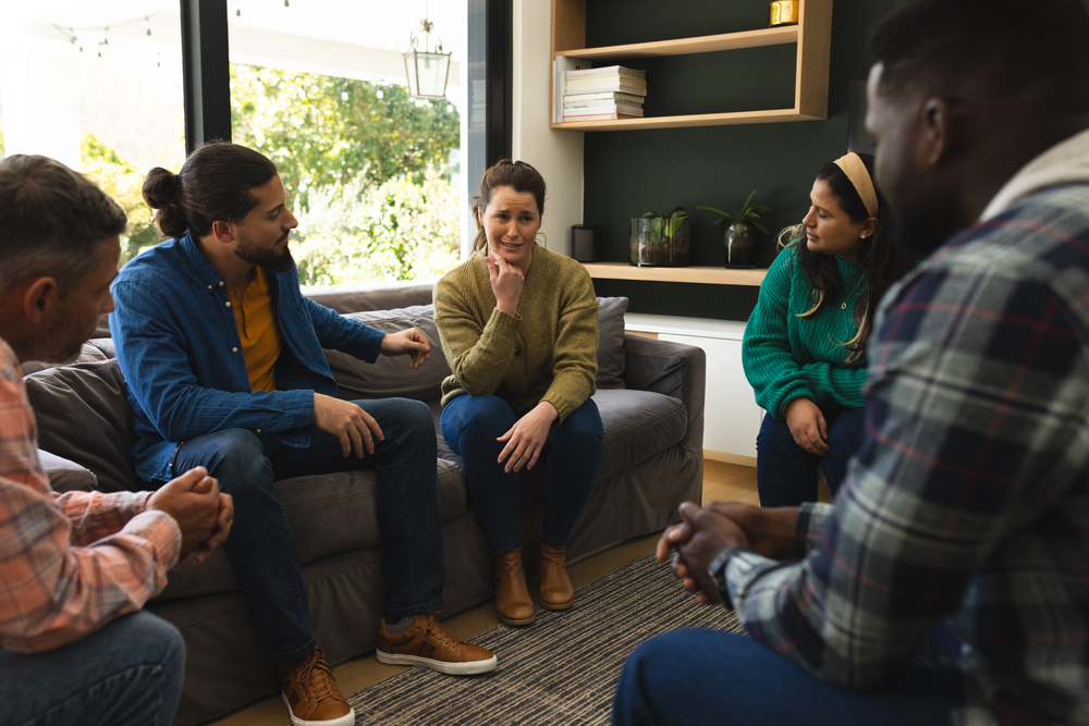 Diverse group of friends talking and supporting each other on therapy session. Mental health, therapy, friendship and support, unaltered. Woman speaking to her peers in a comforting and cooperative group therapy setting