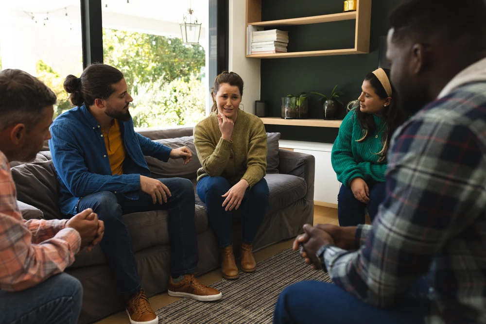 Diverse Group Of Friends Talking And Supporting Each Other On Therapy Session. Mental Health, Therapy, Friendship And Support, Unaltered. woman speaking to her peers in a comforting and cooperative group therapy setting