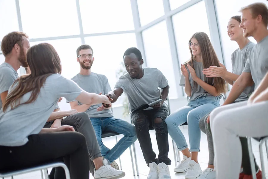 Diverse Group Shaking Hands And Clapping In A Supportive Opioid Addiction Treatment Group Session diverse group shaking hands and clapping in a supportive opioid addiction treatment group session