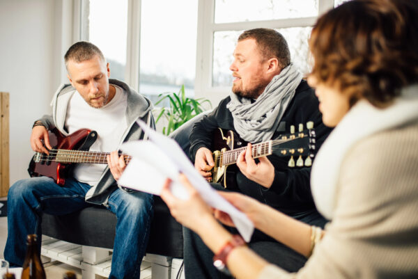 Group music session with individuals playing instruments, guided by a certified music therapist, promoting relaxation and self-expression for addiction recovery as part of the music therapy program