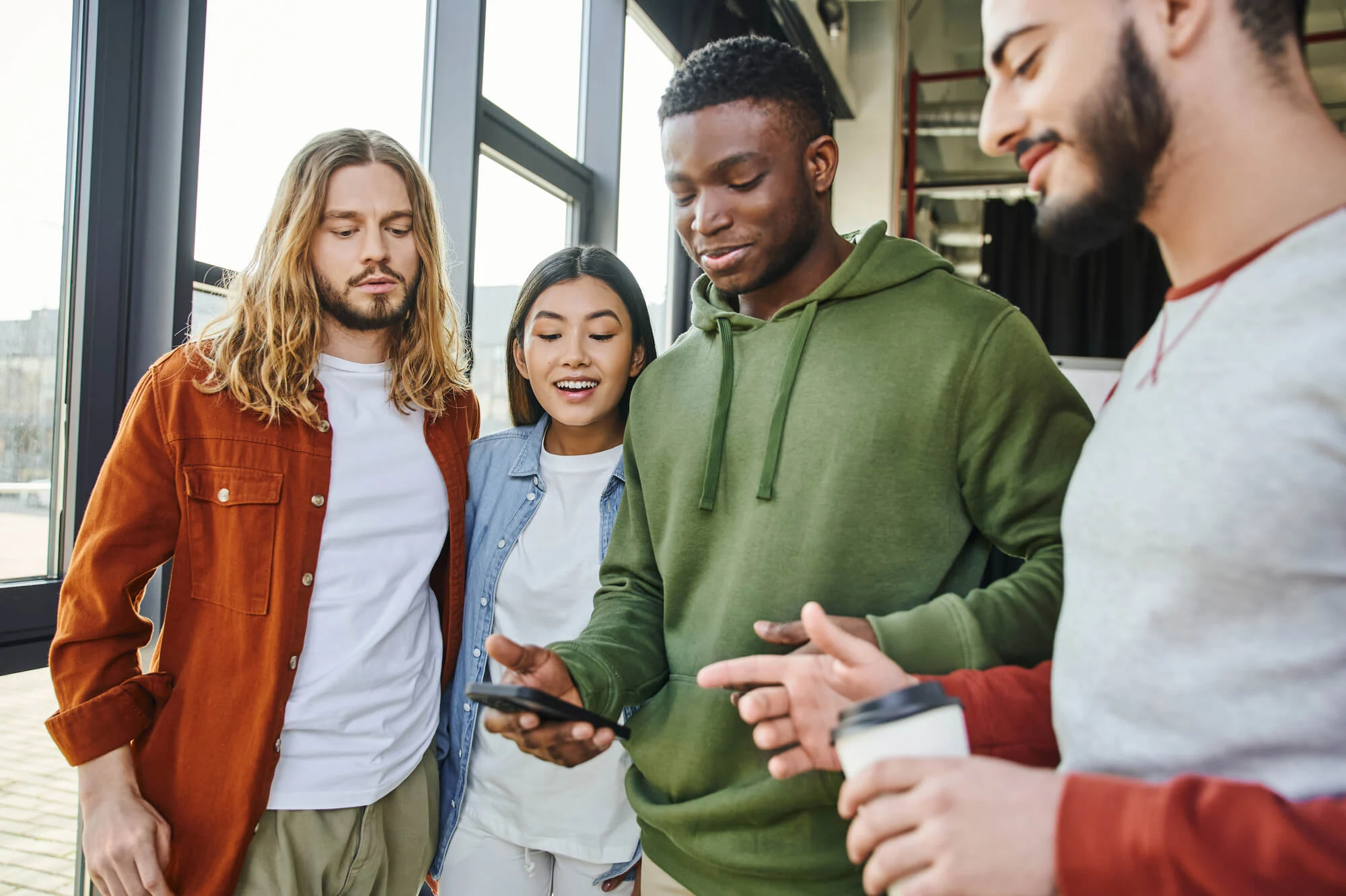 Medicaid Coverage For Mental Health Treatment group of diverse friends looking at a smartphone, illustrating community support available through montana medicaid coverage for mental health treatment.