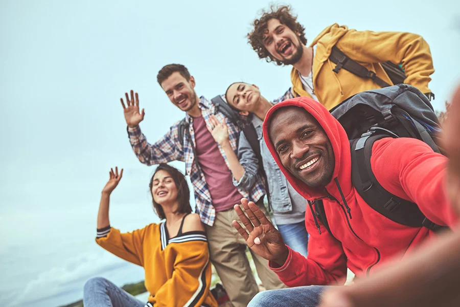 group of friends outdoors smiling and waving, representing camaraderie in veteran rehab programs with experiential therapy