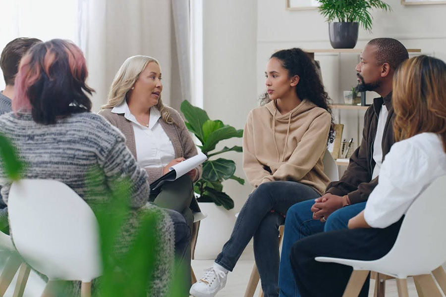 group therapy session with counselor and adults discussing treatment options inpatient vs php vs iop in outpatient setting