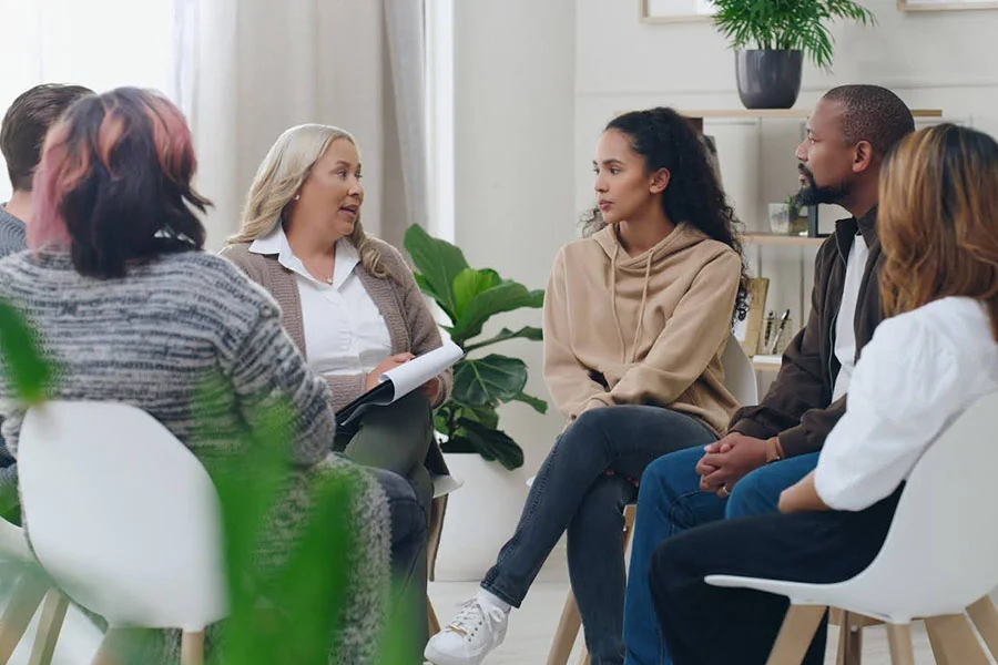 group therapy session with counselor and adults discussing treatment options inpatient vs php vs iop in outpatient setting