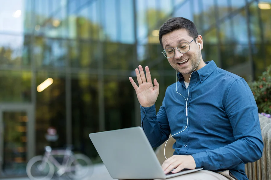 man on laptop video call with earbuds during viop for substance use treatment