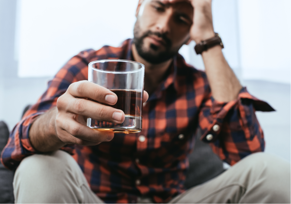 Man holding a glass of whiskey, possibly contemplating Alcohol Addiction therapy Man holding a glass of whiskey, possibly contemplating alcohol use disorder therapy