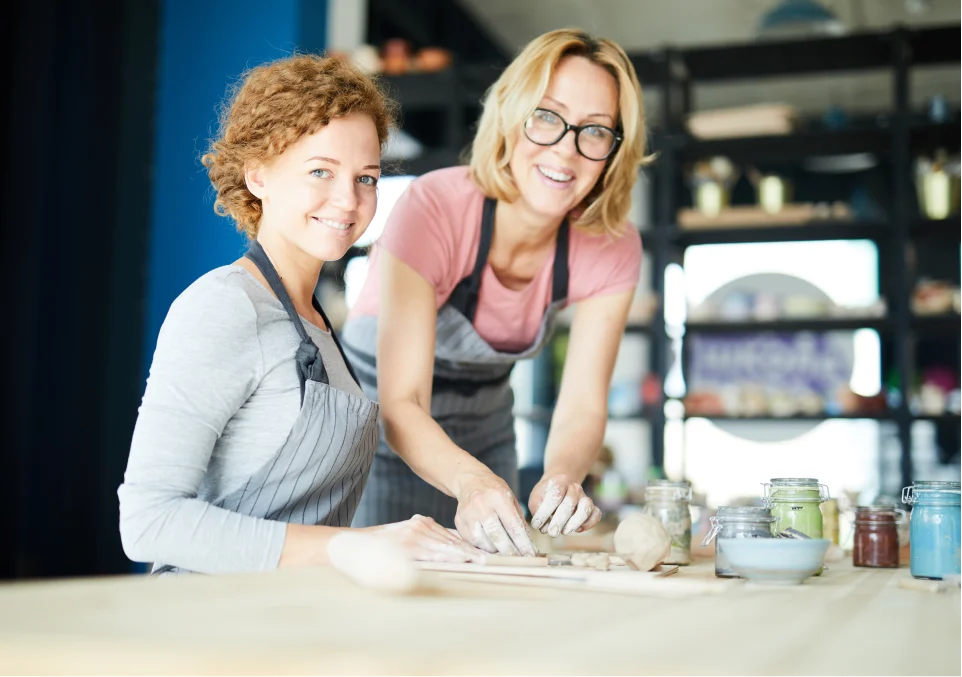 two women smiling while making pottery in an experiential therapy session