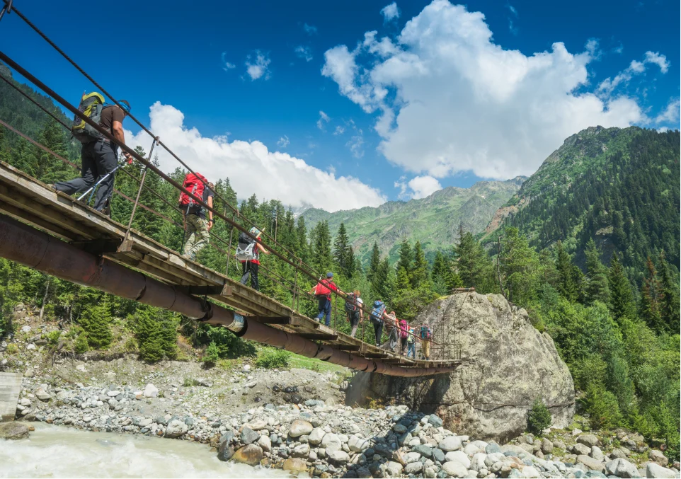 hikers crossing a bridge in the mountains as part of an adventure therapy excursion