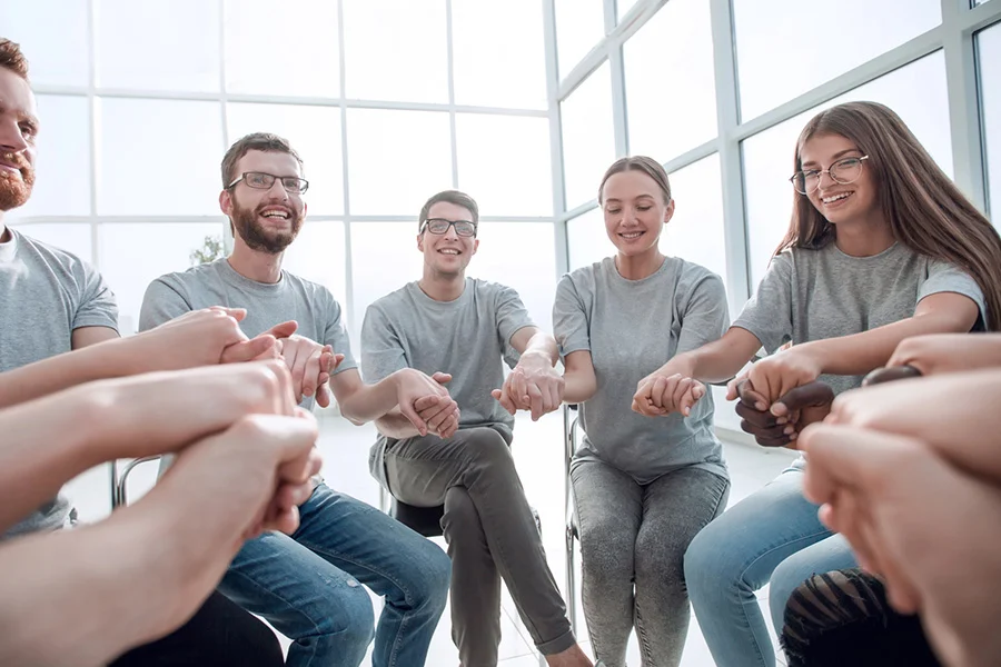 support group holding hands in a circle during treatment for substance use