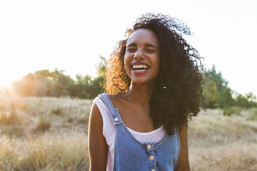 woman smiling outdoors in a sunlit field, associated with recovery from fentanyl abuse and wellness