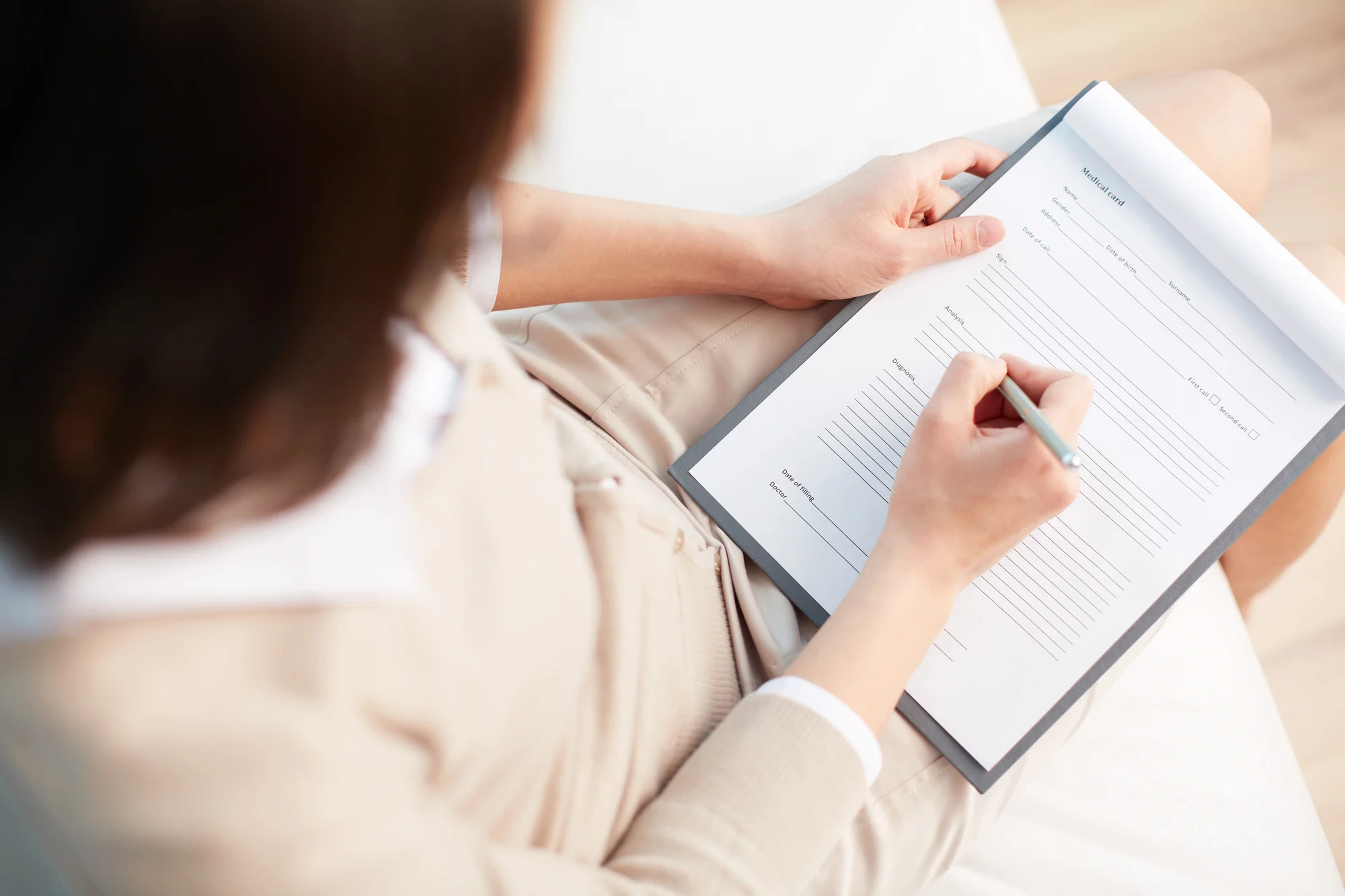 a woman fills out medical paperwork for allegiance by cigna addiction admissions at a treatment center.