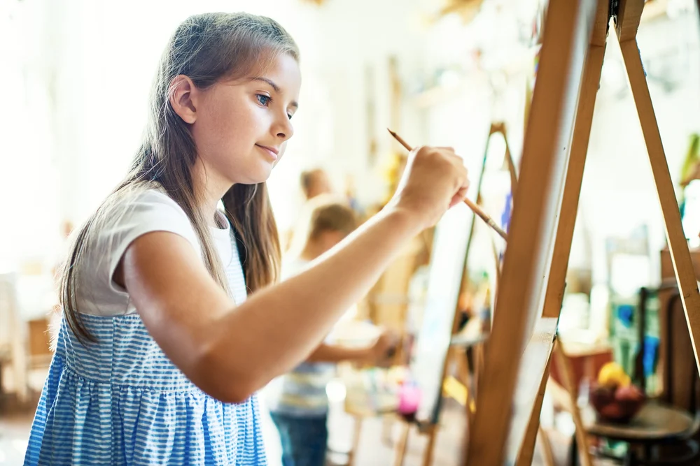 a teenage girl painting on canvas during their art therapy for children in kalispell, mt