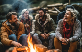 group of friends laughing around a campfire in a wilderness therapy setting