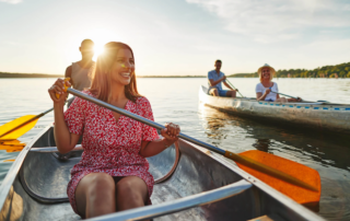 smiling woman canoeing with friends on a lake during an outdoor therapy session