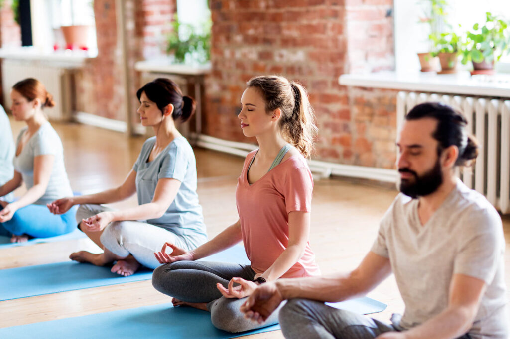 Adults practicing mindfulness meditation in a wellness group session.