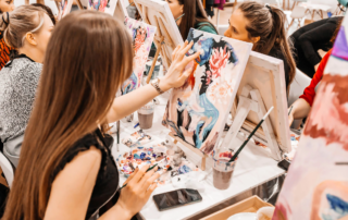 group of individuals painting on canvases in an art therapy class