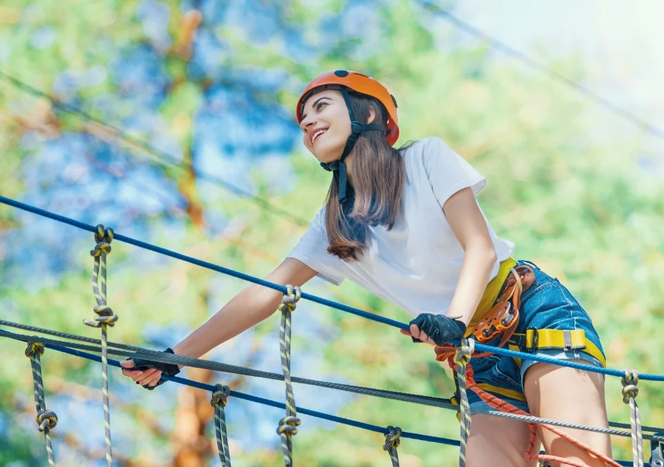 smiling woman on a high ropes course, possibly as an adventurous part of fentanyl addiction treatment therapy
