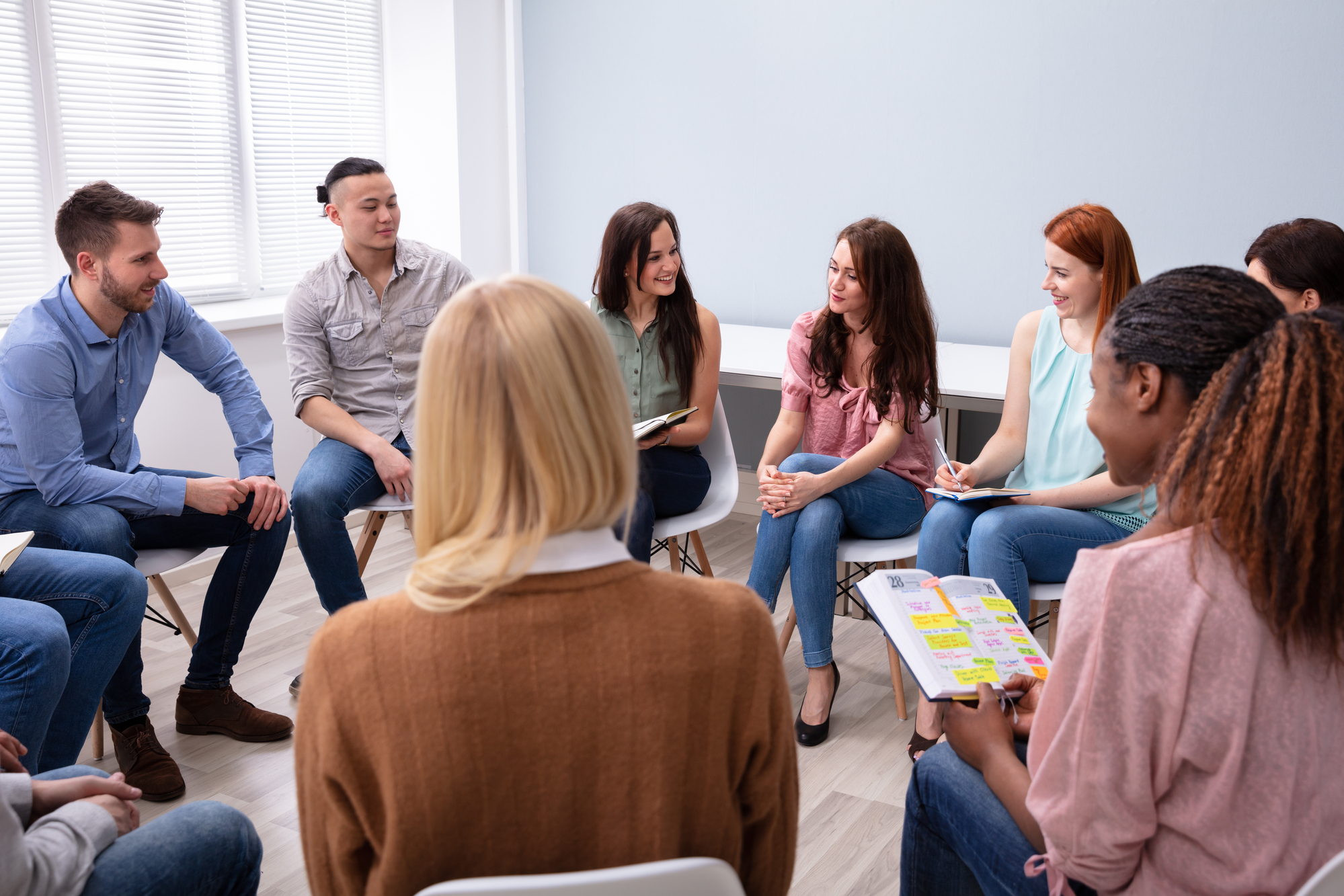 Participants in the substance use disorders group therapy listen intently to their therapist.