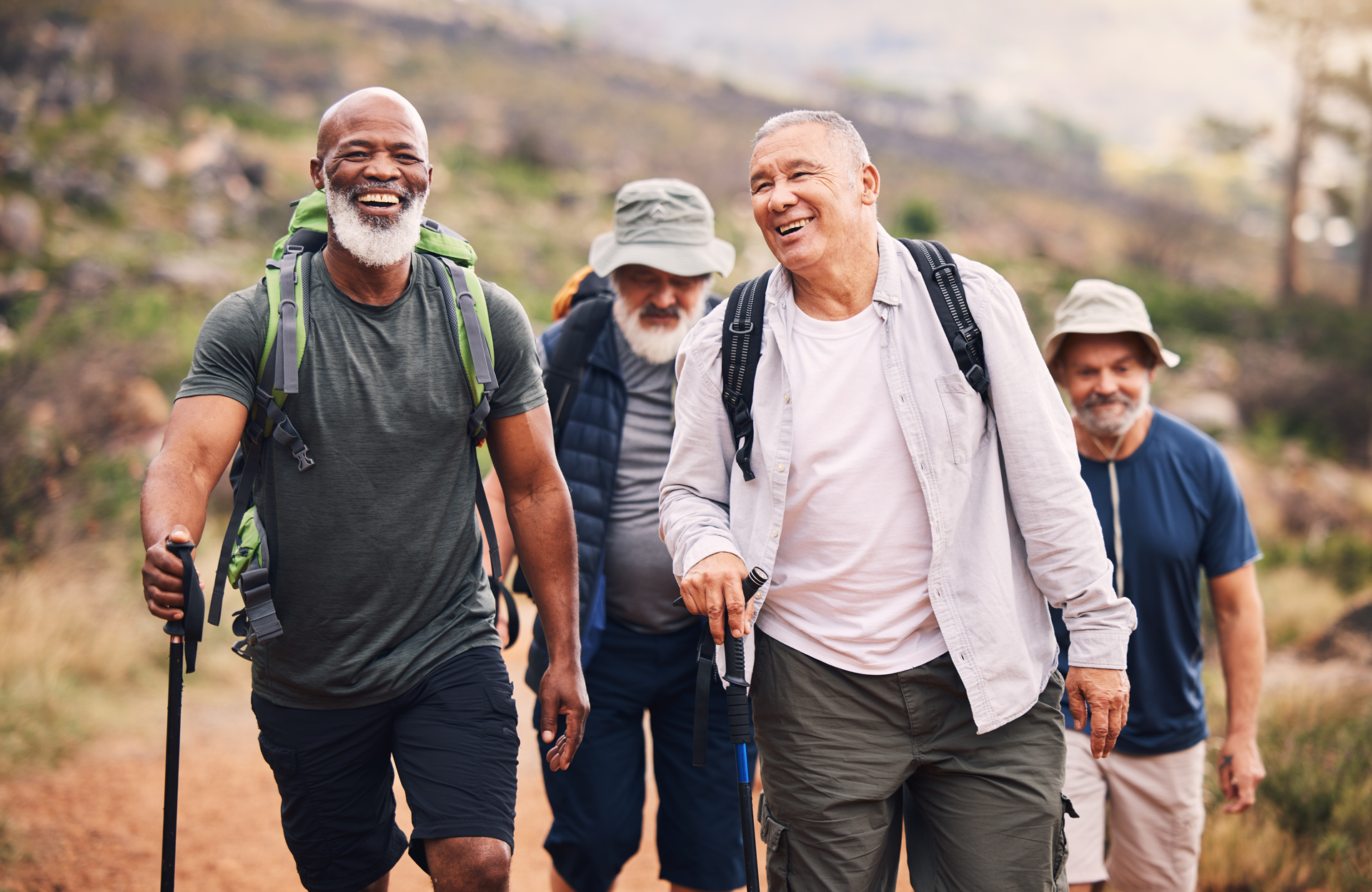 Group of senior men bonding and laughing on a healing nature walk for PTSD recovery Group of senior men bonding and laughing on a healing nature walk for PTSD recovery