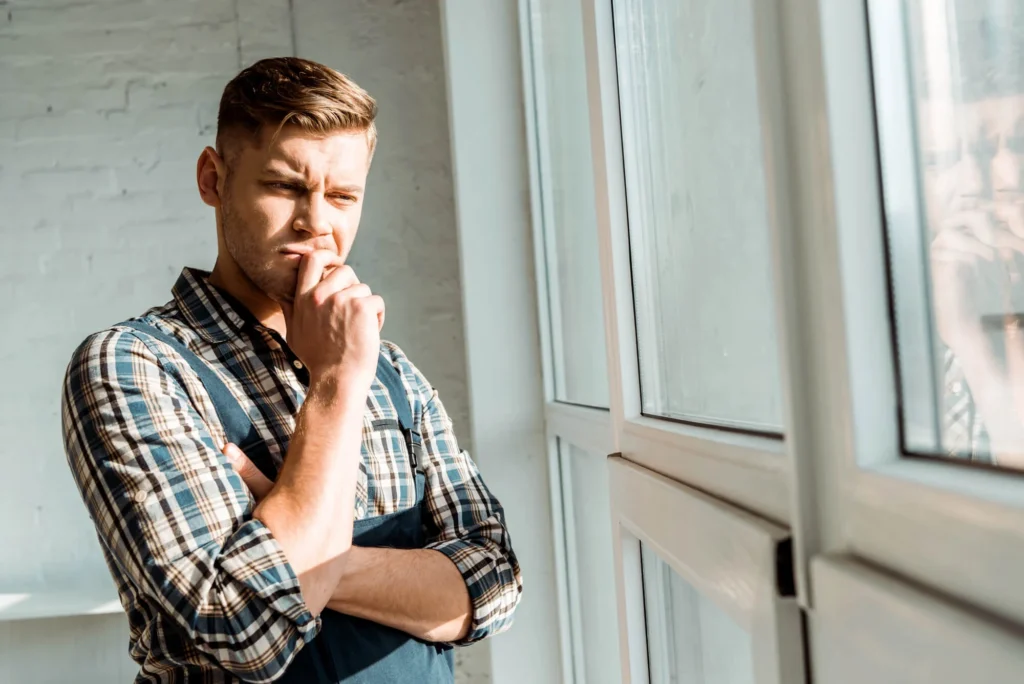 man looking out window thinking about sex addiction