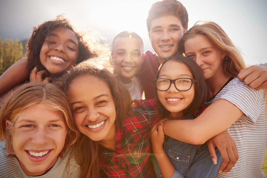 Group of happy teens huddled in sunlight, a positive image for teen substance abuse programs
