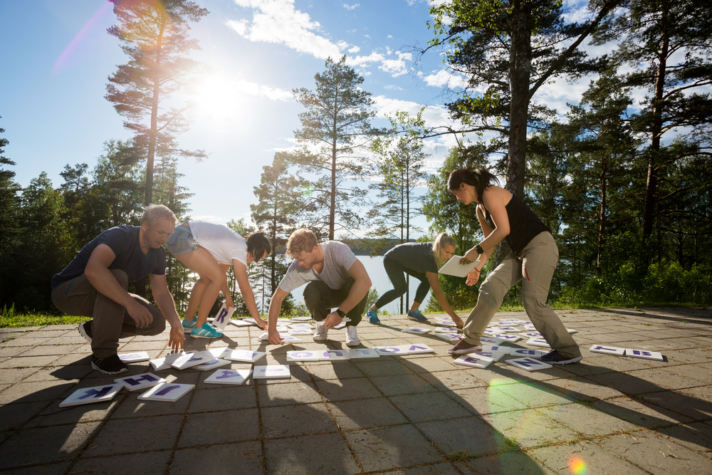 Full length of group therapy participants solving crossword puzzle on patio in forest